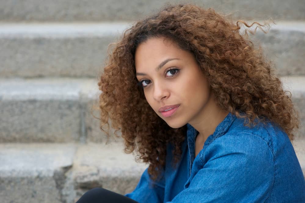 Beautiful black woman with dark roots creating a shadow effect on her natural curls.