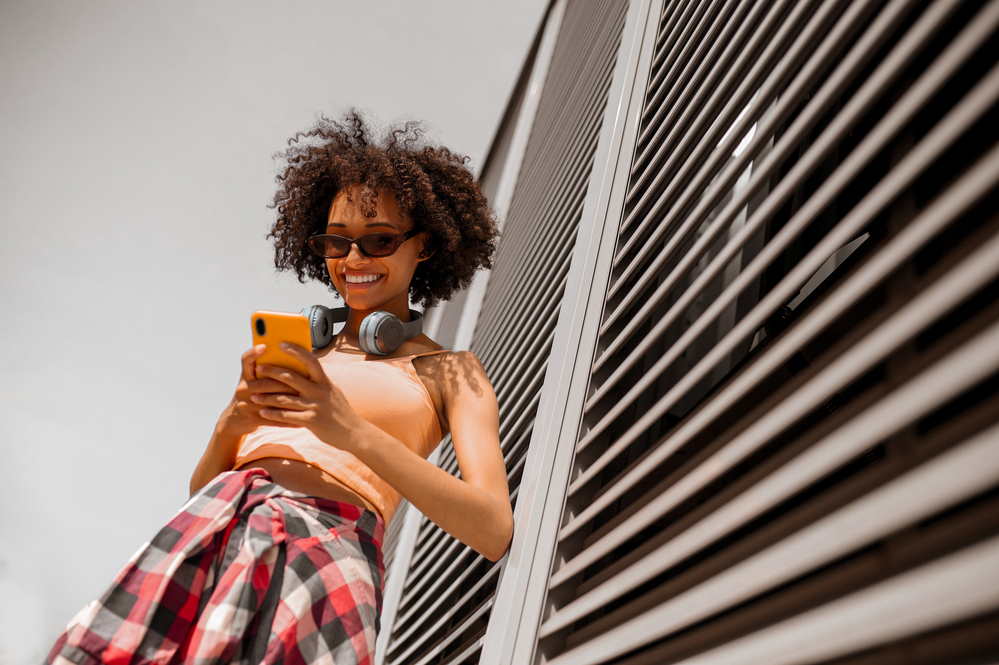 A mixed-race female is texting one of her guy friends about what's he wearing tonight to a company party.