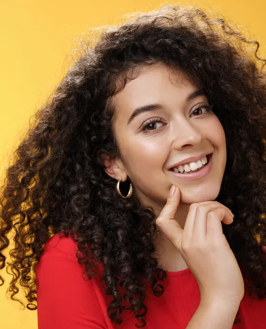 A cute white lady wearing a red shirt with curly permed hair curled with perm rods.