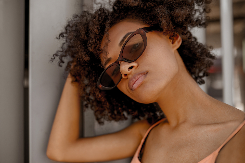 A dark-skinned woman with a new haircut showing off her perfectly styled wash n go hairdo.