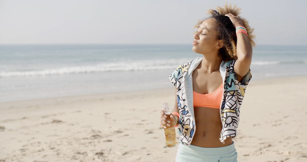 Happy black woman on vacation wearing a curly wash n go hairdo with semi-permanent hair dye.