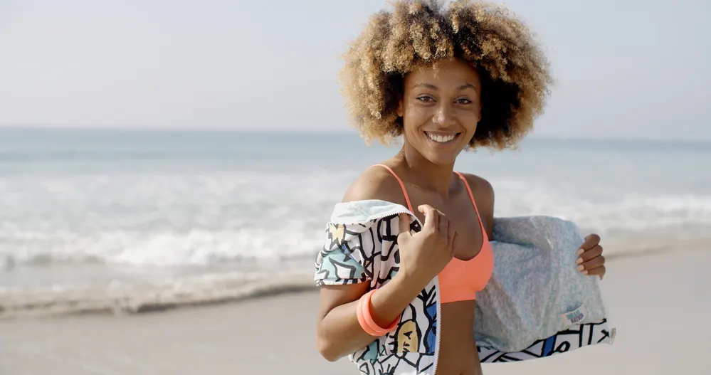 Will My Hair Fall Out If I Bleach It? Twice? Too Much? 1 Cute African American female with blonde bleached hair walking in the sand at the beach.