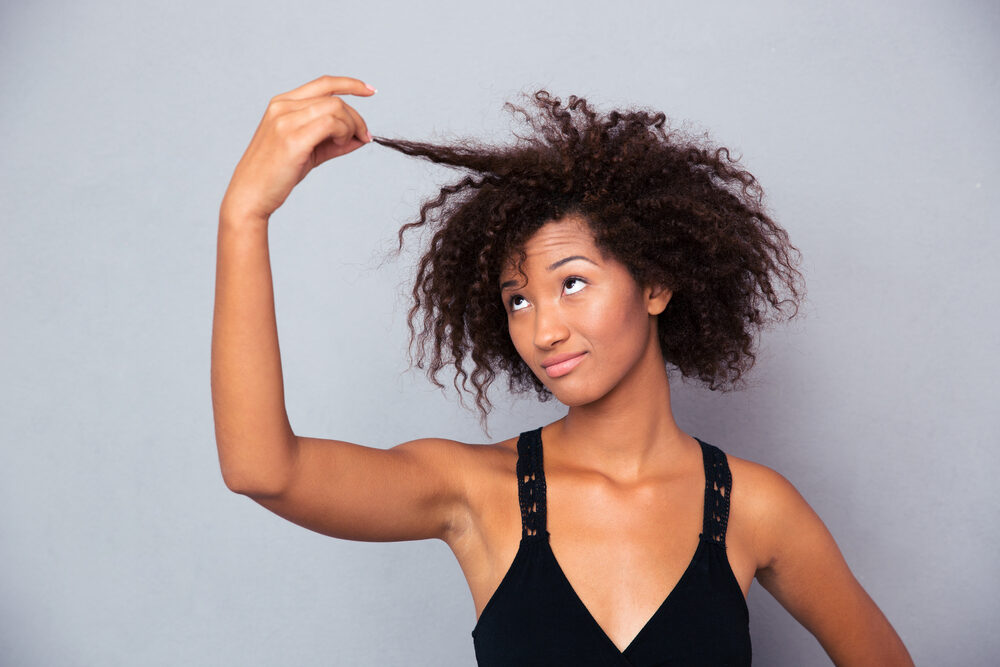 African American woman dealing with hair fall (hair loss) checking her hair strands.