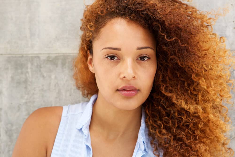 Beautiful mixed-race female with naturally curly hair colored with auburn permanent dye