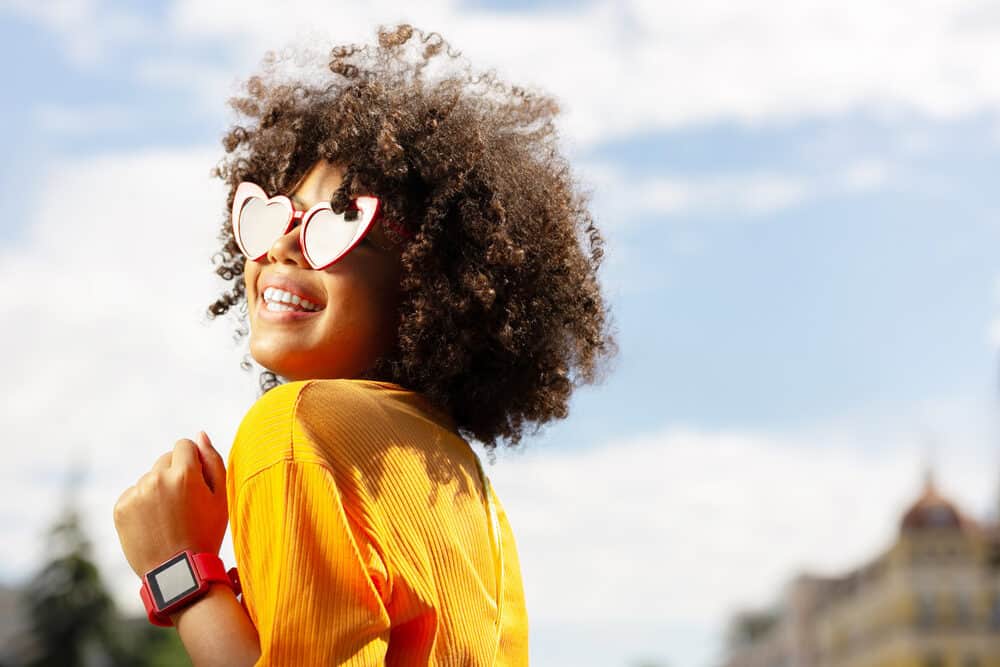 Black girl laughing while wearing heart-shaped sunglasses.