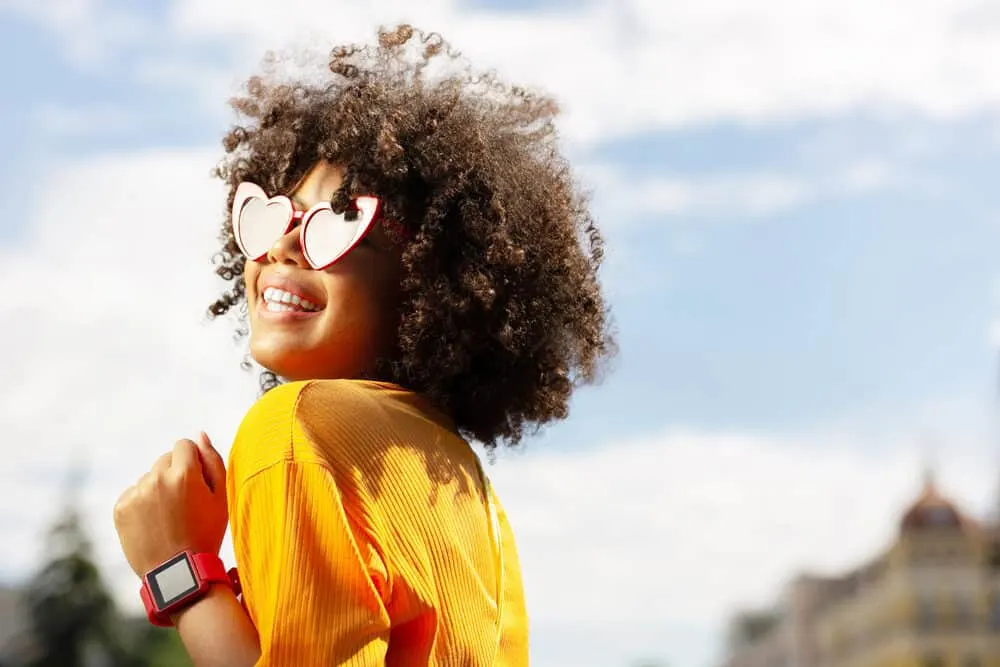 Black girl laughing while wearing heart-shaped sunglasses.