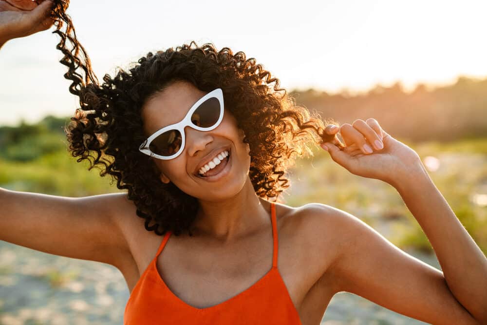 Amazing black woman at the beach with a 4A curly hair type coconut hair oil and Shea Moisture leave-in conditioner.