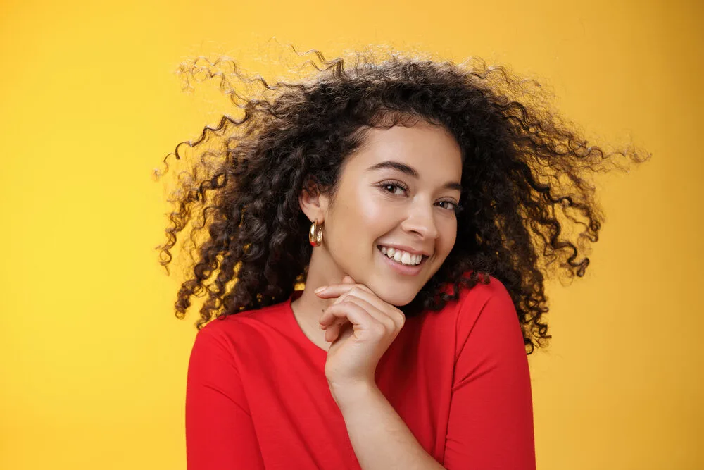 Pretty woman with chemically treated hair that's been curled with rollers to maintain her weakly formed curls.