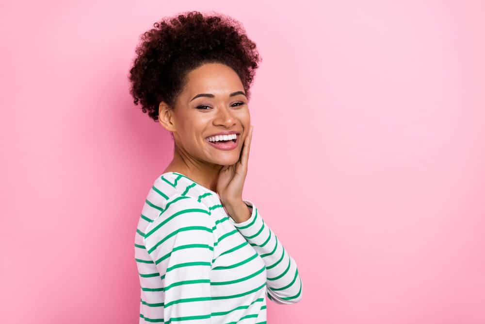 An attractive girl with hair porosity issues on 4A curls wearing pink lipsticks and freshly arched eyebrows.