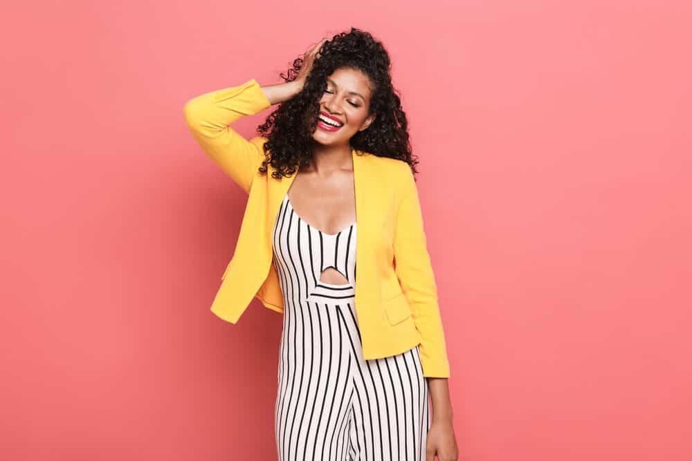 Lady with bouncy curls created with a curling iron wearing a business casual yellow, black and white outfit.