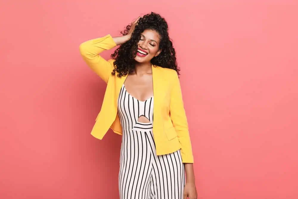 Is Curly Hair Attractive? Why? What Do Guys Think? 5 Lady with bouncy curls created with a curling iron wearing a business casual yellow, black and white outfit.
