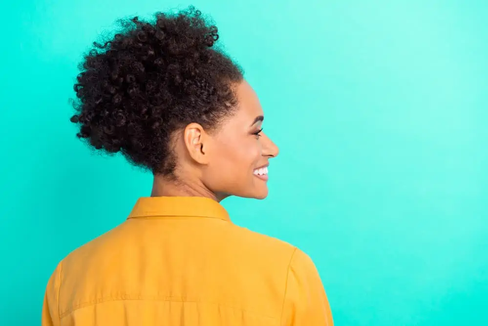 Beautiful black lady showing off the reduced hair loss after taking a water-soluble supplement of biotin.