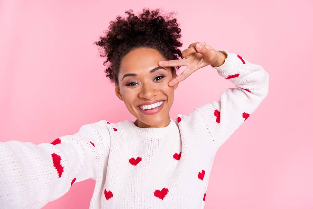 Young lady taking a selfie to show off her own hair to family and friends after a semi-permanent hair color treatment.