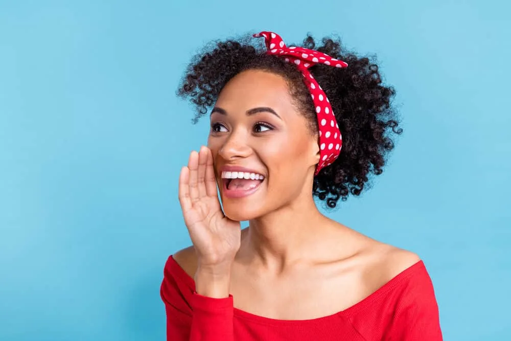 Cute black with oily hair wearing a casual red shirt and red and white bandanna with natural make-up.