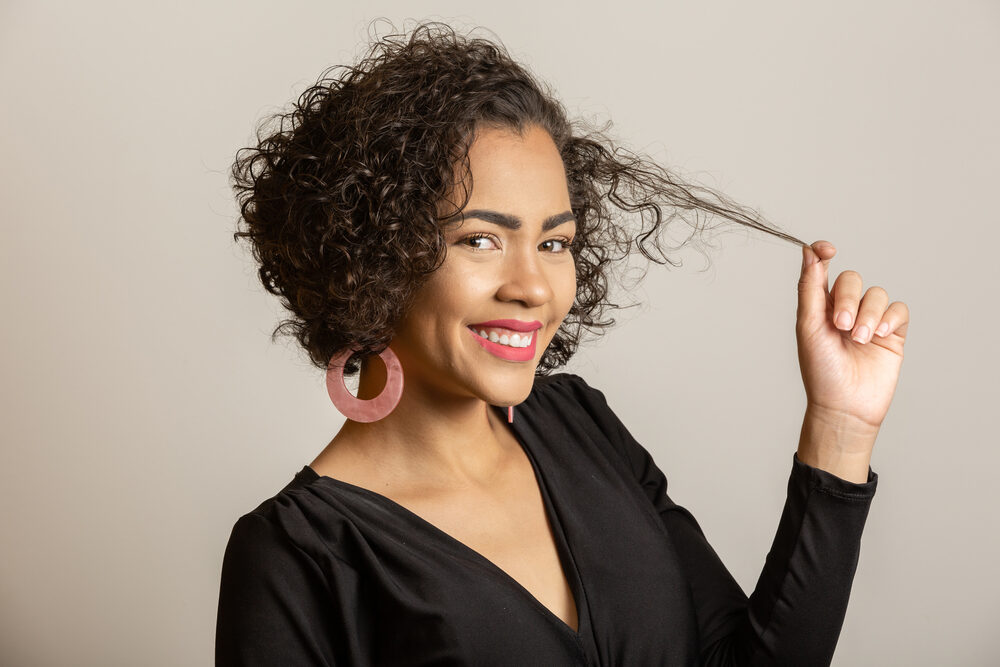 Female with damaged hair follicles from frequent hair dyeing wearing a casual black dress.