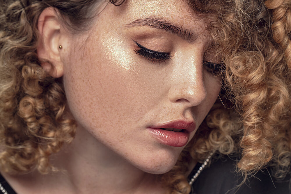 Elegant white girl with subtle freckles and chemically treated hair gently styled after a curly perm.