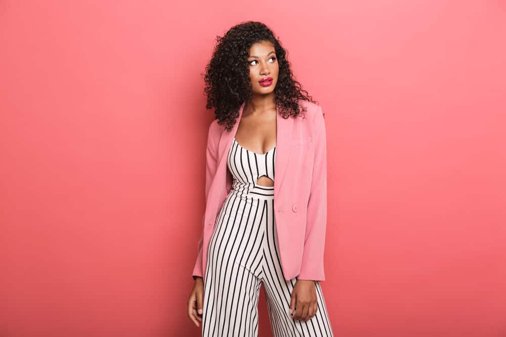 Stylish black woman wearing a black and white jumper with a pink jacket on dark unbleached hair.