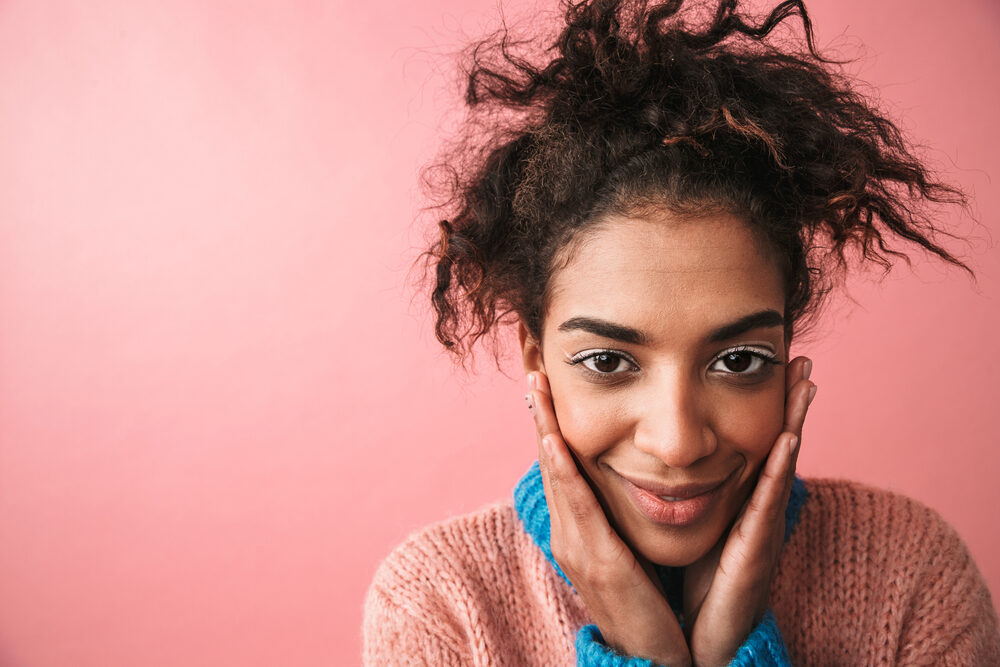 Happy young black girl with a great smile and poor hair health using Olaplex treatments to prevent further damage.