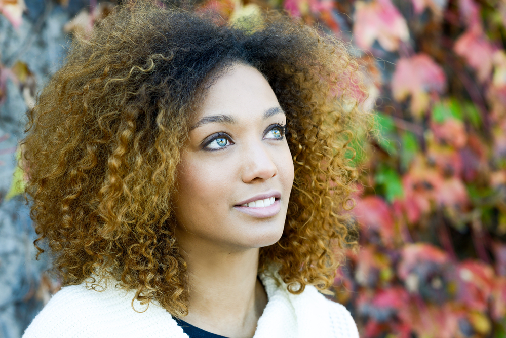 African American female with color-treated hair and blue eyes enjoying the weather on an autumn day.