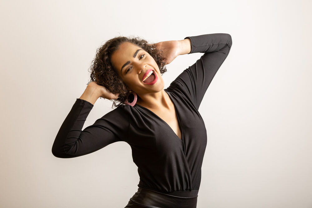 African woman with poor hair growth wearing a black dress with pink hoop earrings.