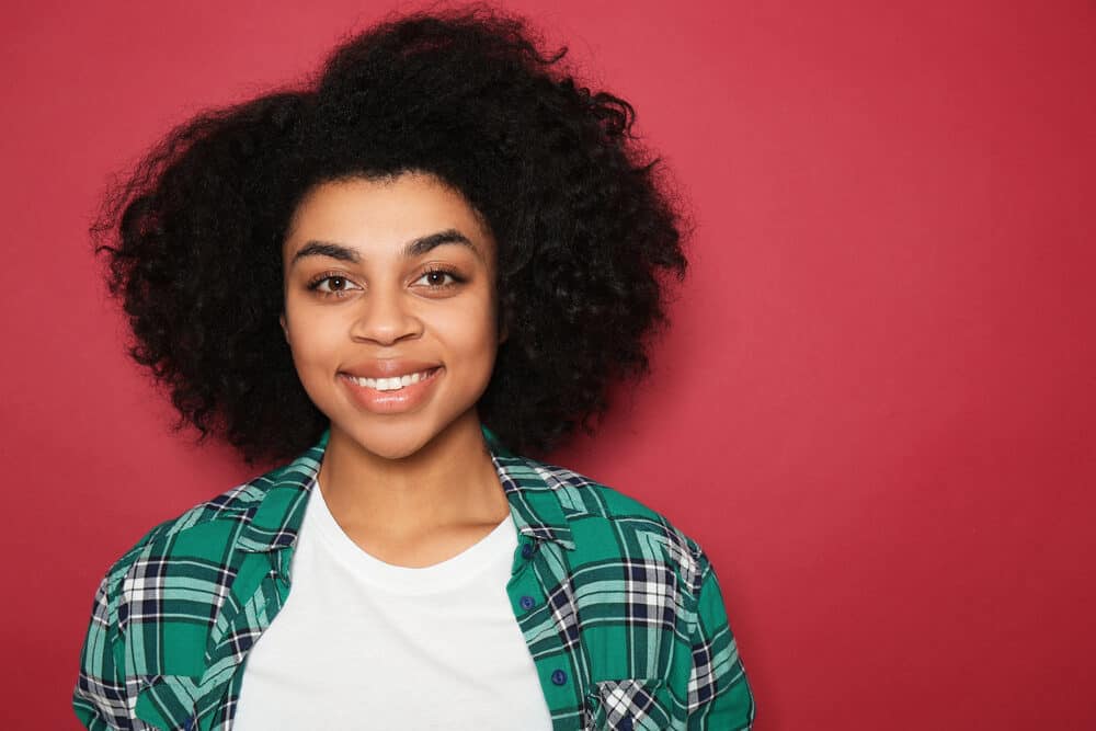 A cute African American woman with 4A curls treated with henna hair dye wearing a casual white t-shirt.