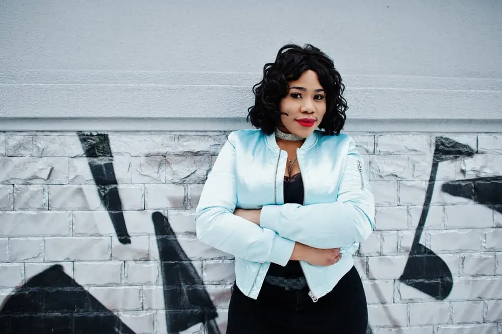 Does Short Hair Make You Look Fatter or Thinner? Plus Tips 1 Stylish African American woman with an oval face shape and short hair length wearing a blue jacket.