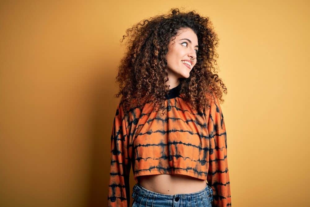 Caucasian female with natural curls wearing Russian hair extensions with brown and blonde highlights.