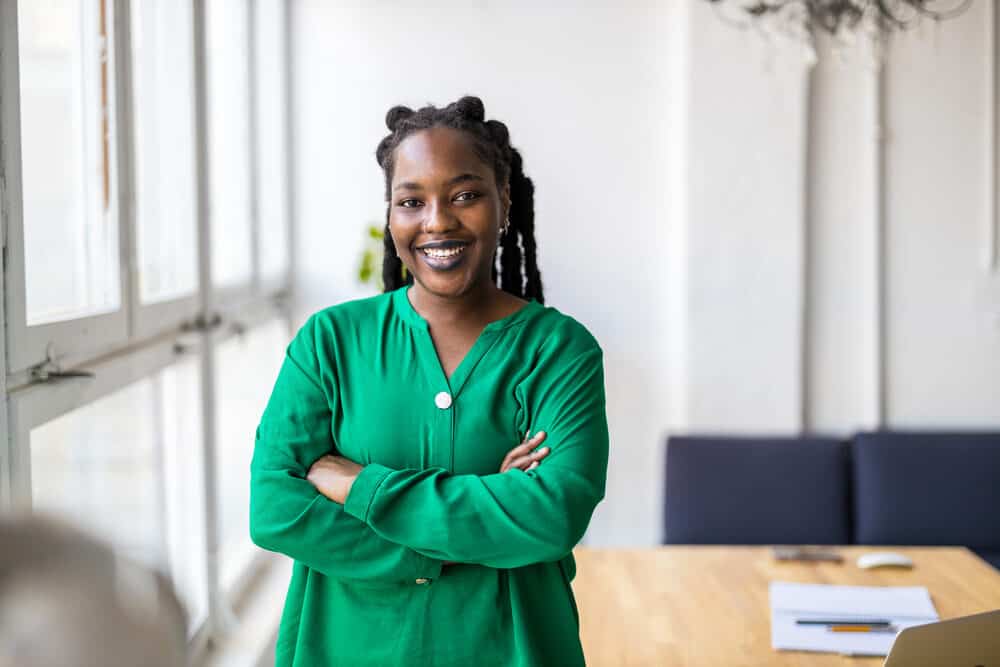 Black female with thinner dreads researching hair loss and healthy roots on her laptop in the kitchen.