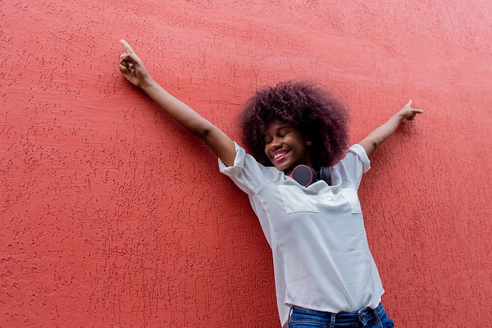 A happy African American lady with 3B curls with purple hues following the hair coloring chemical process.