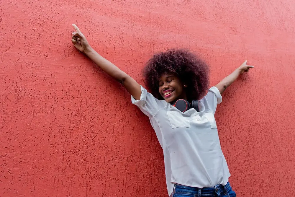 Is It Better to Dye Clean or Dirty Hair To Get the Best Results? 6 A happy African American lady with 3B curls with purple hues following the hair coloring chemical process.