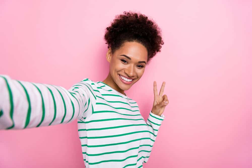 Black lady wearing casual clothes with a curly updo that's a dark brown natural color styled with essential oils.