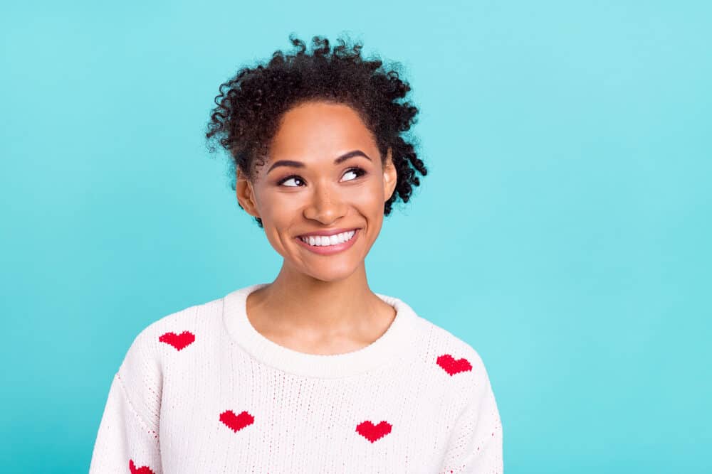 Attractive black female with metallic dyes on bouncy 4B curls looking curious with a cute smile.