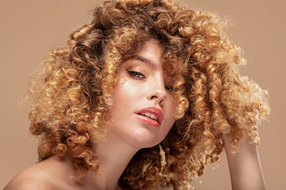 A woman wearing her hair loose after a perm solution styled with natural oils.