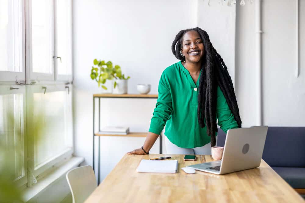 African American lady researching how hair grows to prevent further hair loss while taking notes at the kitchen table.