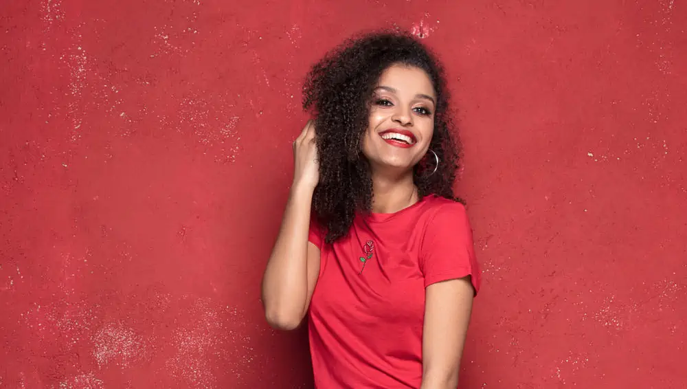Should You Brush Curly Hair? Wet or Dry? Everyday? Before Bed? 5 Lady with 3B hair keeping her curls smooth by brushing hair with her fingers and a detangling brush.