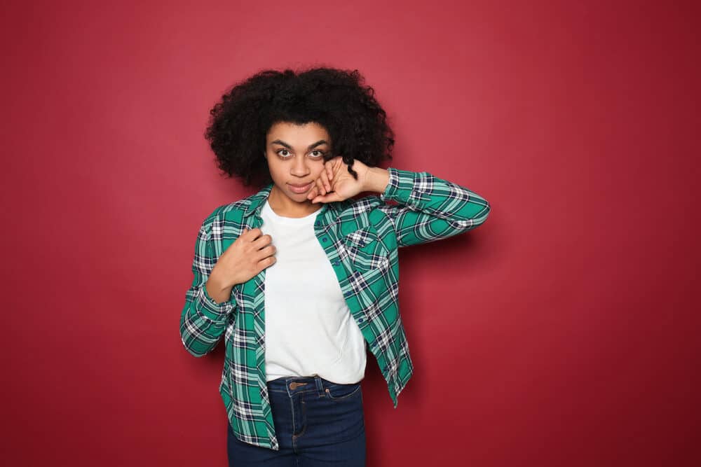 Attractive African American lady with 4A curls wearing a white t-shirt, blue jeans, and a flannel shirt.