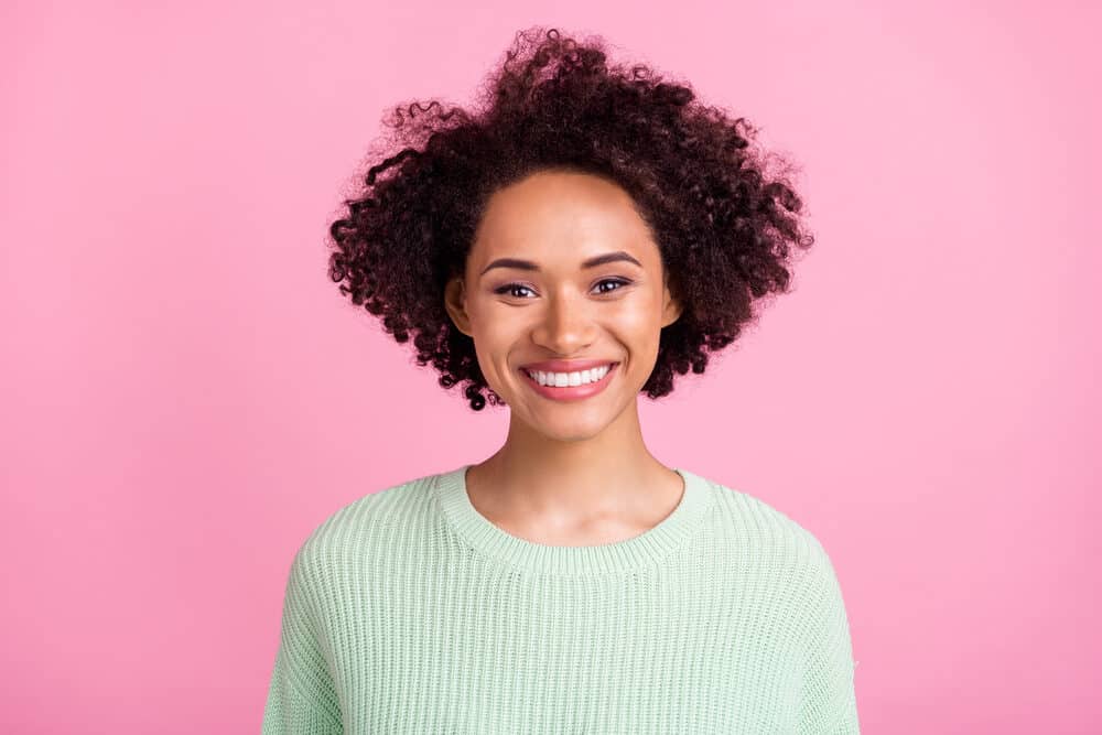 Cute African American female with 3B dark brown hair wearing a light green sweater.