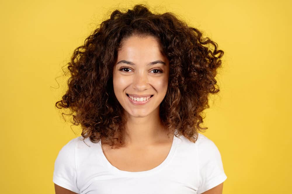 Cute African American female wearing Splat hair dye from a professional colorist on dark brown curls.