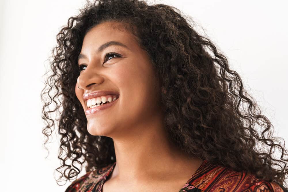 Black lady with a great smile suffering from scalp irritation and braid bumps after wearing a tight protective hairstyle.