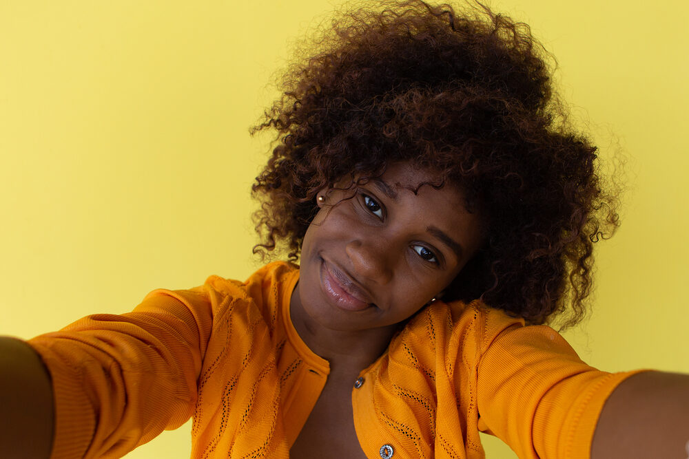 How To Tell If Your Hair Is Damaged: 5 Damage Signs & Fixes 1 African American female with lifeless brittle hair that's lacking moisture due to excess heat styling.