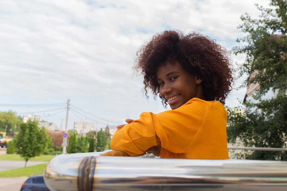 Cute African American female with unhealthy hair care practices causing damaged hair follicles.