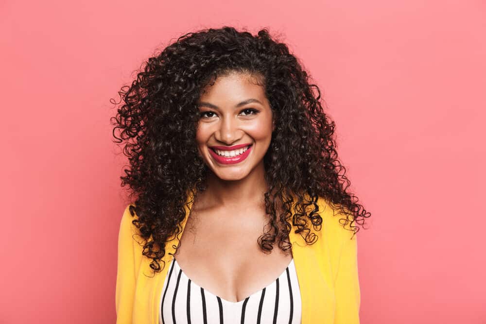 Beautiful African American female with naturally curly hair wearing a black and white jumper with a yellow jacket.