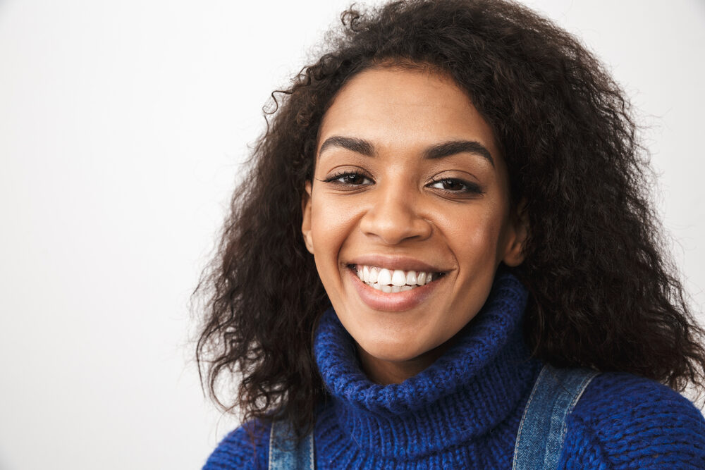 African American woman with frizzy hair and split-ends on 3C natural curls wearing a blue sweater.