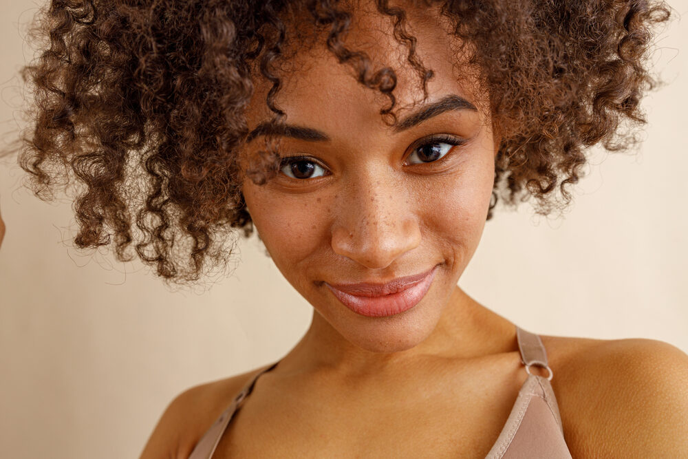 Beautiful mixed race lady with cute freckles and curly hair styled with hair powder.