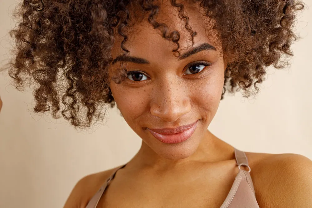 Is Volume Powder Bad for Your Hair? What Is It? Is It Safe? 1 Beautiful mixed race lady with cute freckles and curly hair styled with hair powder.