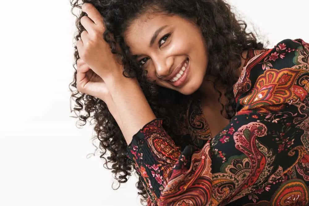 How To Get Rid of Tension Bumps on Scalp: Will They Go Away? 9 Attractive young African American female wearing a dress rubbing her fingers through her natural 3B curls.