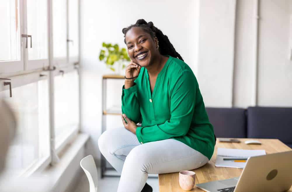 A woman wearing a green casual shirt and jeans reading about how to keep her hair healthy.