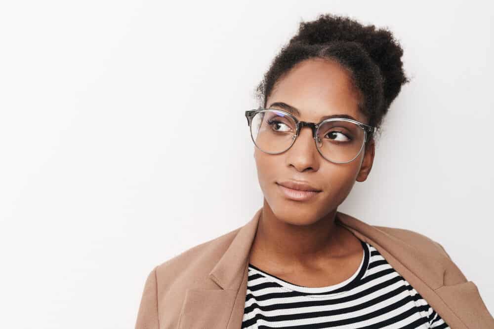 Beautiful black girl with black curly hair wearing a brown jacket and casual clothes.