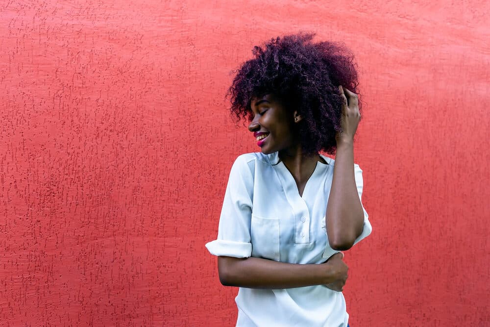 Black with naturally curly 4B curls wearing a white nurse-like casual shirt.