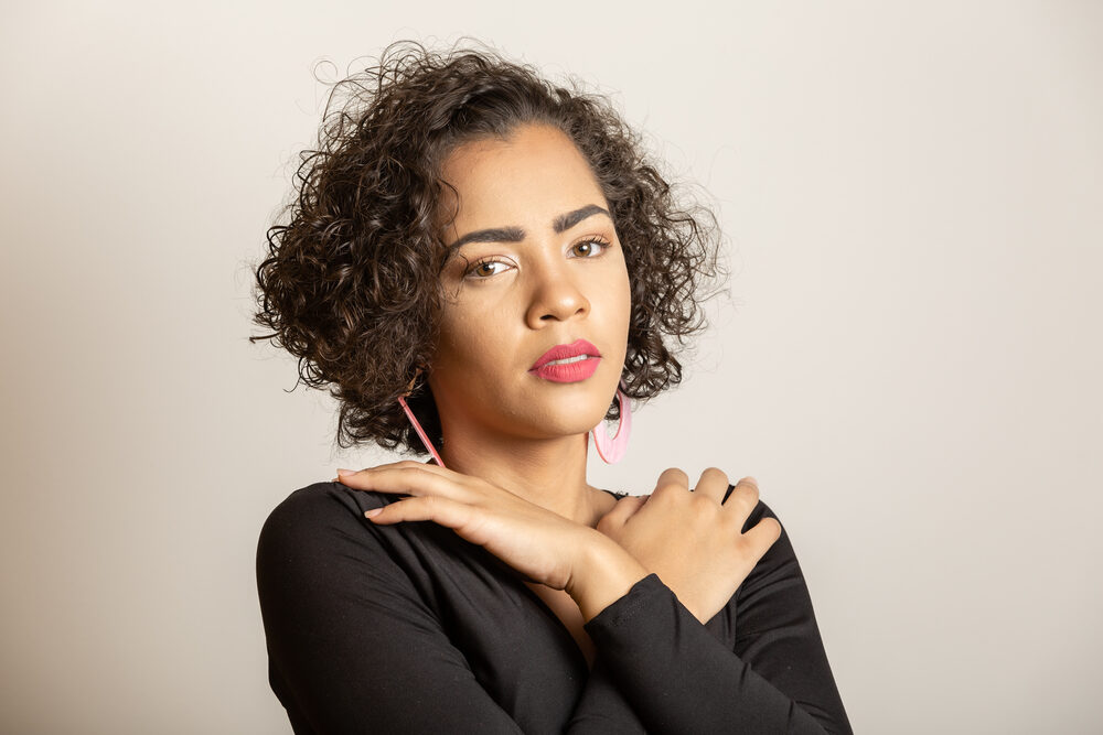 Cute black girl with oily hair using moringa oil for maintaining healthy hair strands.